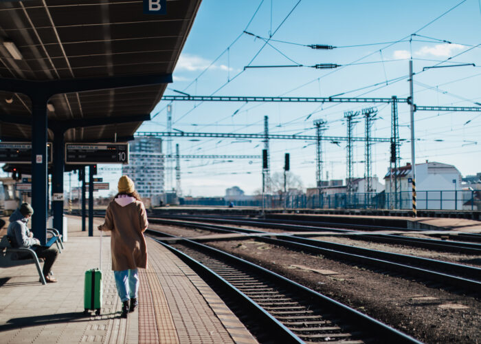 Single person waiting for train with luggage at an outdoor station