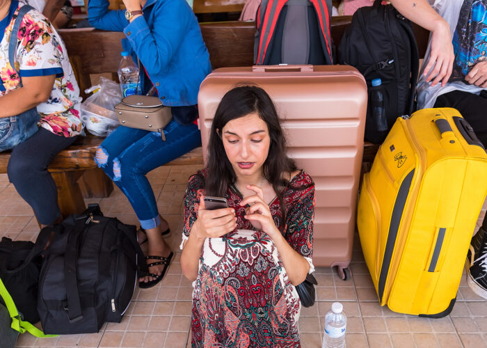 woman studying phone on vacation waiting at train station