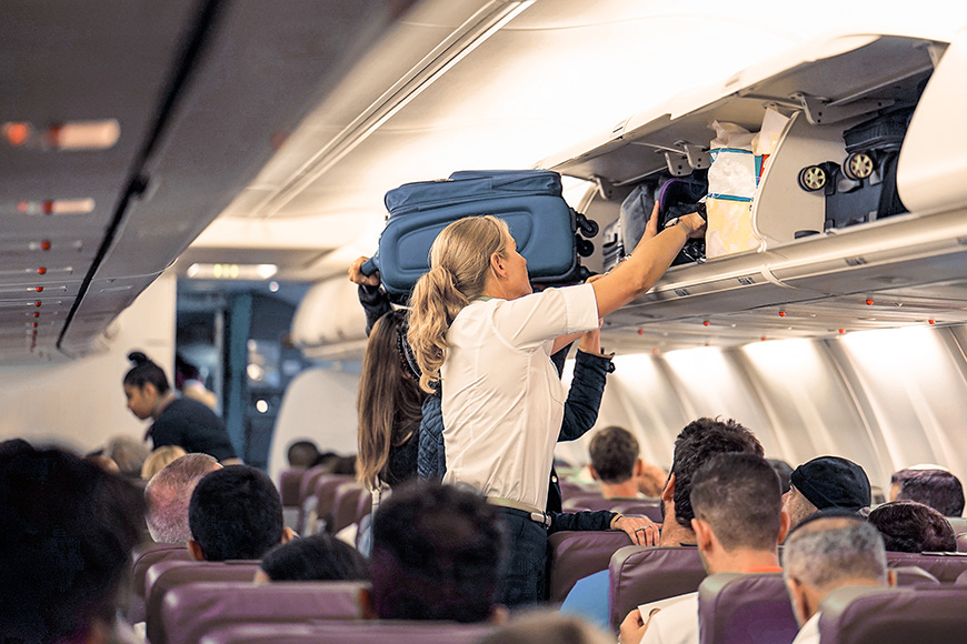 stewardess helps the passengers to put their luggage in the cabin of the plane