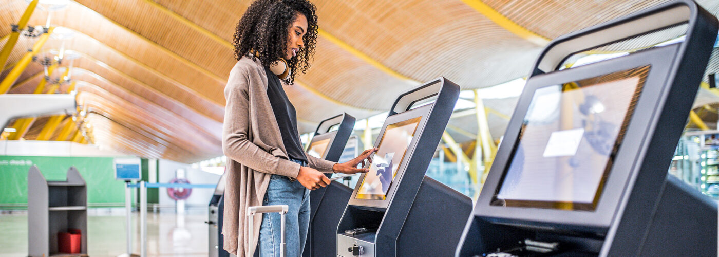 black woman using the check-in machine at the airport getting the boarding pass