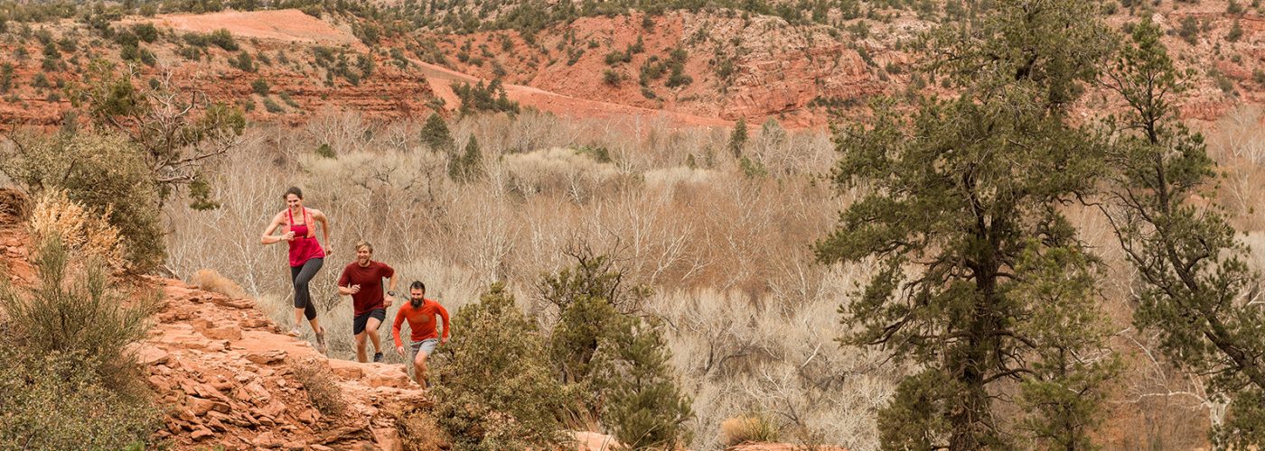 male and female running up canyon in activewear.
