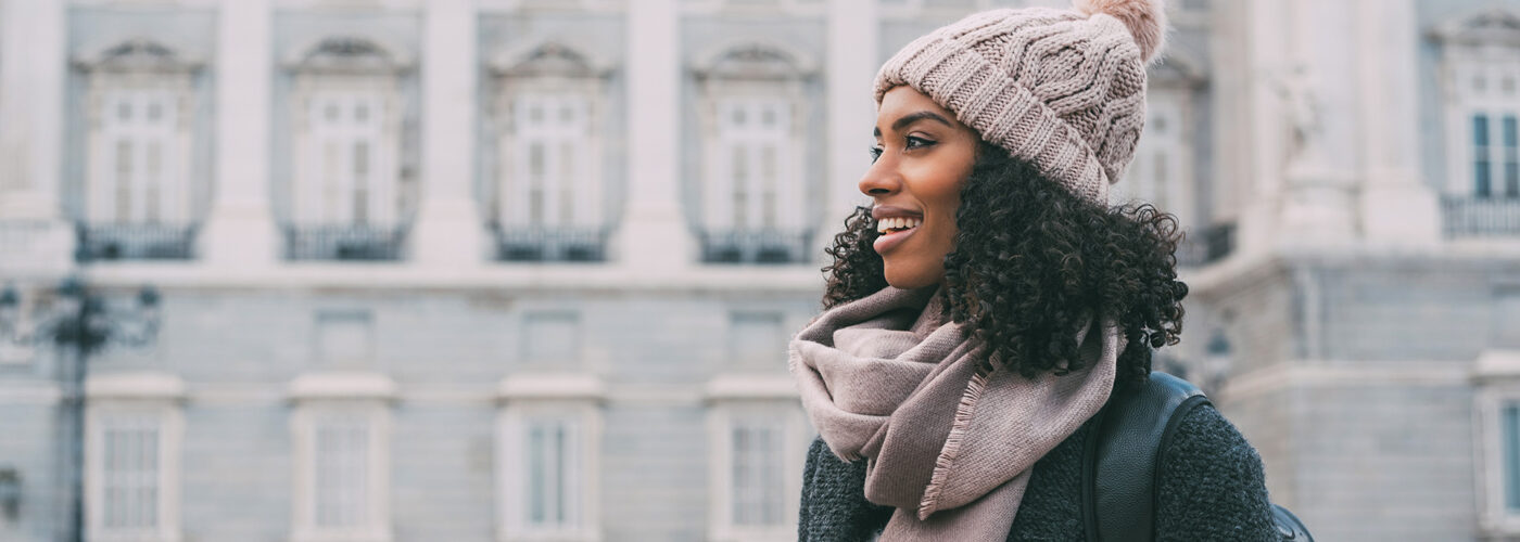 Young black woman drinking coffee wandering in the streets of Madrid on winter tourist