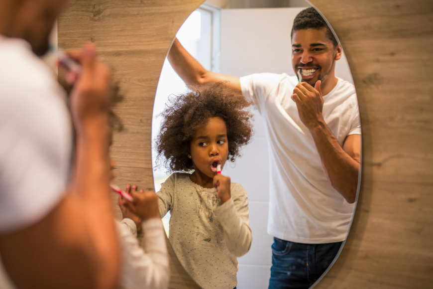 African american girl brushing teeth with dad