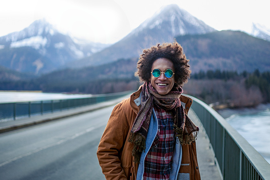 Young man sunglasses is having great time on a bridge with mountains in background