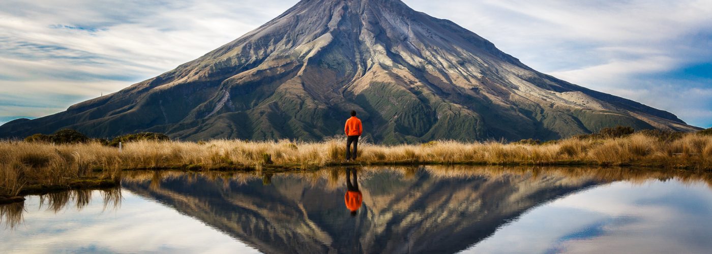 hiker looking at mountain with reflection of water