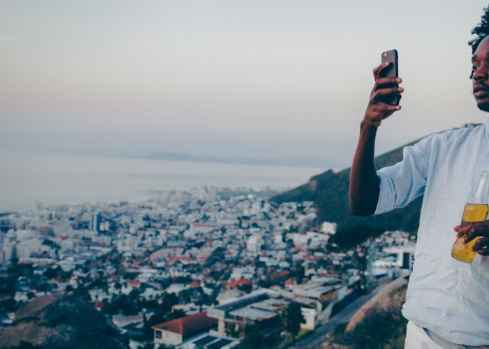man taking smartphone photo of city