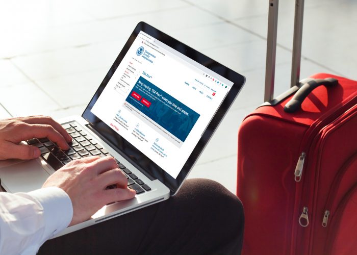 man check TSA Pre website laptop suitcase airport