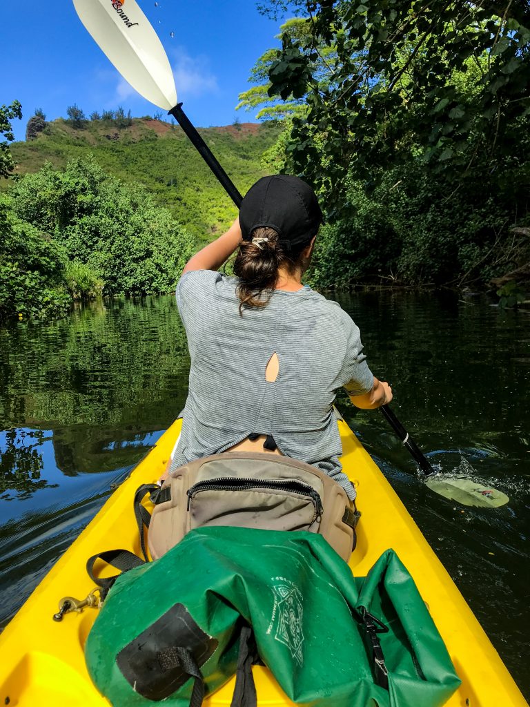 person kayaking on river in jungle.