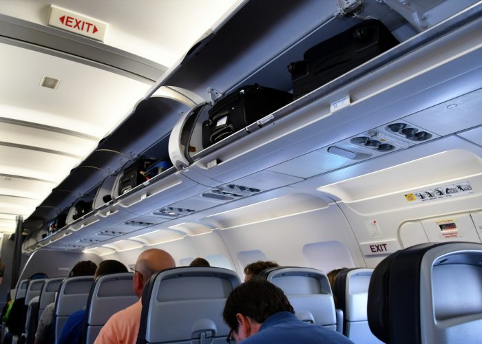 passengers on a plane with overhead bins open.