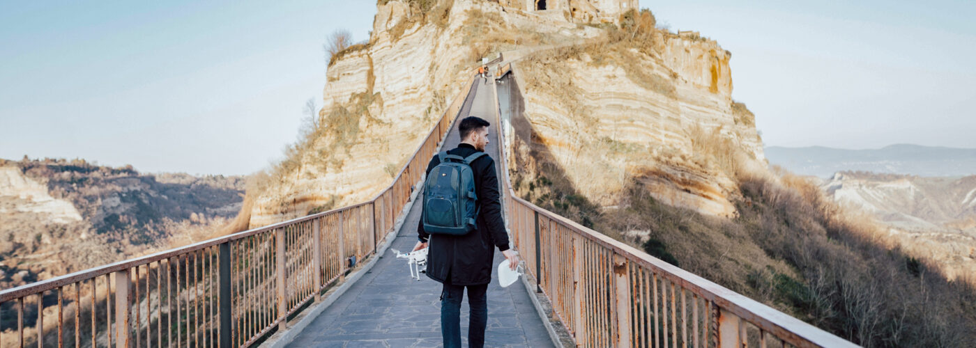 man walking up mountain wearing backpack