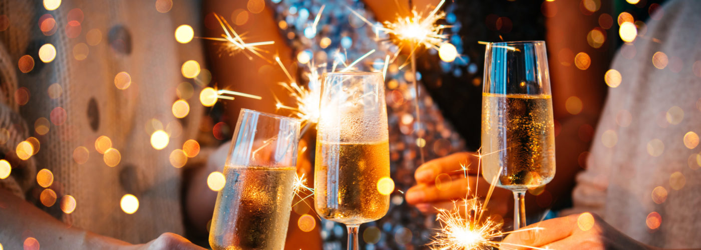 Close up of a champagne toast and people holding sparklers on New Year's Eve