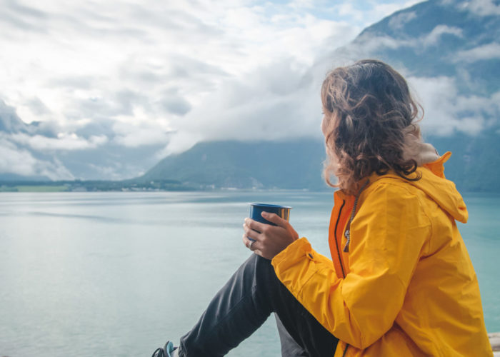 Woman drinking from mug and looking out on fjord