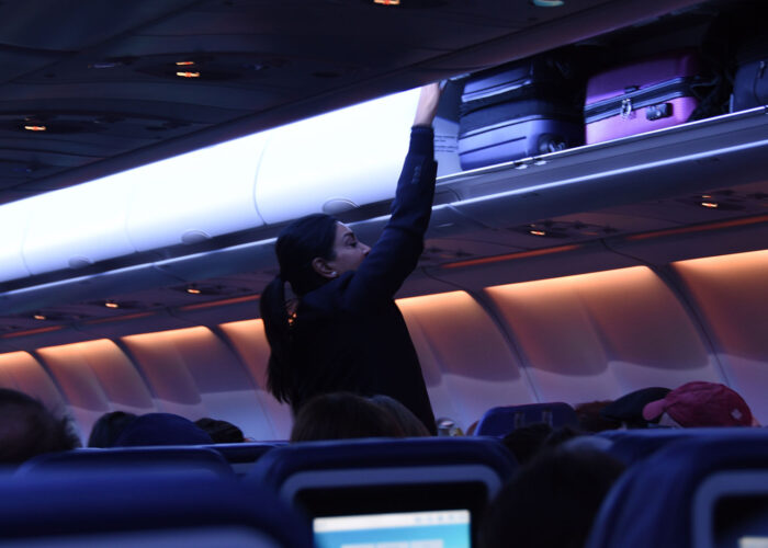 flight attendant closing overhead bin.