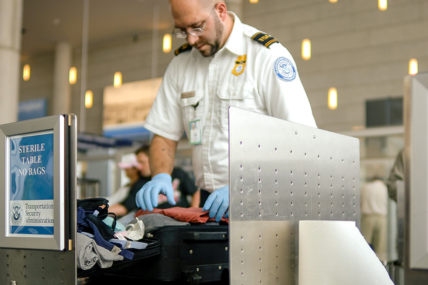 A TSA agent searches luggage at an airport.