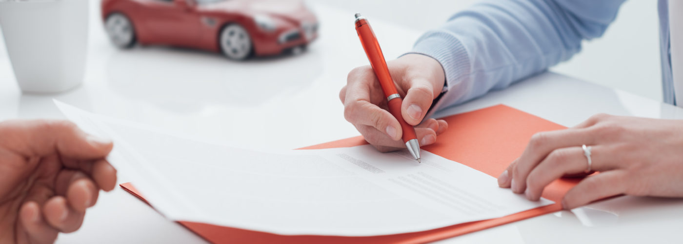 Person signing car rental agreement with a small model car in the background