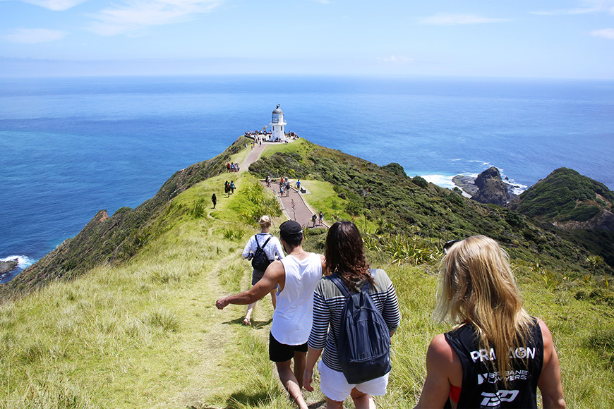 Sweet as Travel hikers walking down path at cape reinga
