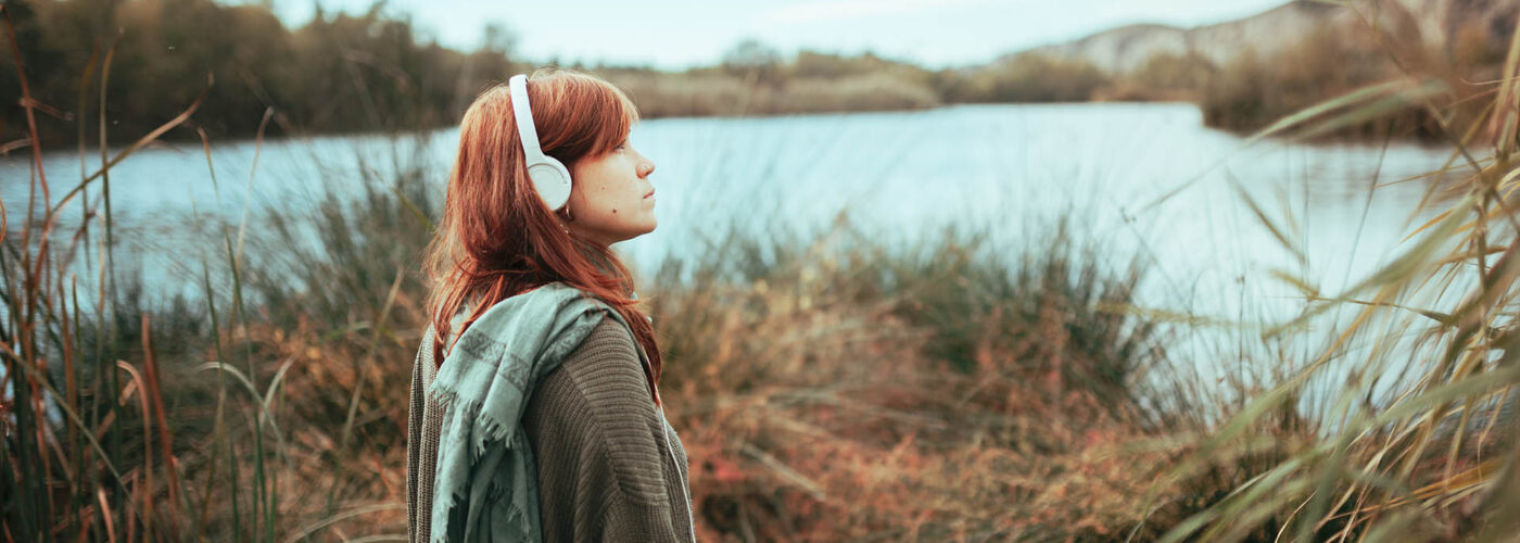 woman with headphones at lake.
