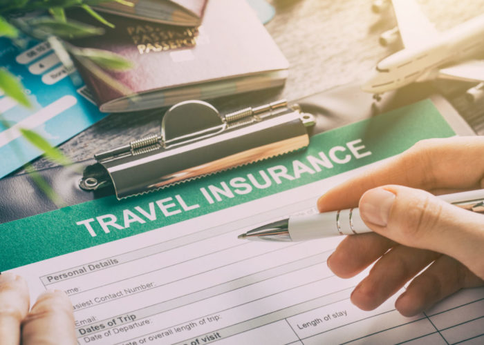 Person filling out travel insurance forms on decorated table