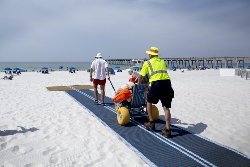 Person using a beach wheelchair to access a beach in Pensacola, Florida