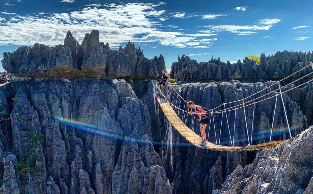 Woman looking over the edge of a rope and wood bridge above a ravine