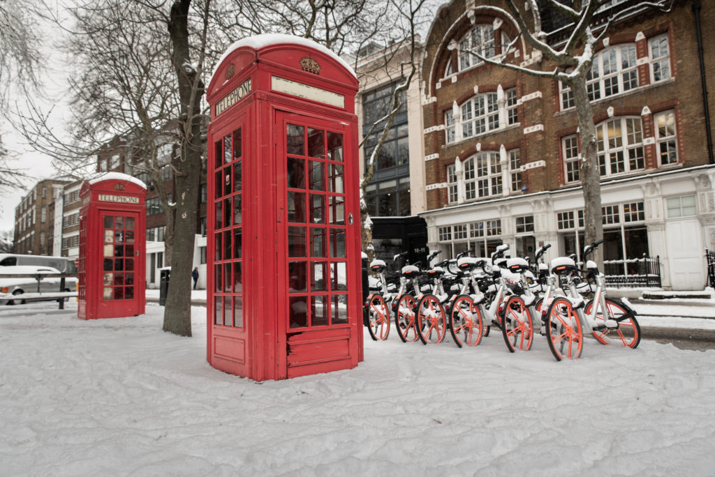 Two phone booths covered in snow on a London street