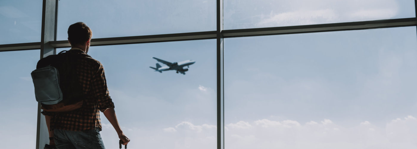 Man watching plane take off from airport window
