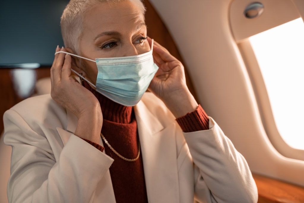 Woman putting on a medical face mask on a plane