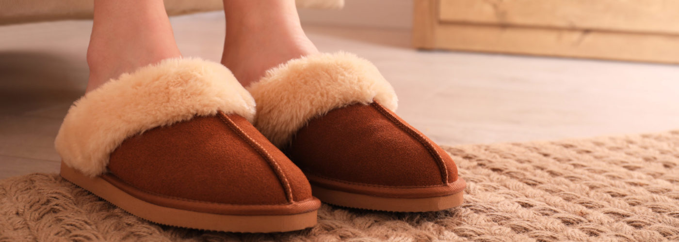 Close-up of person's feet in slippers in house