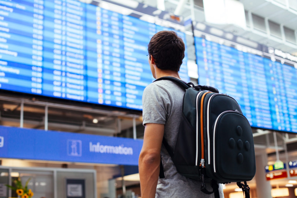 Person with backpack looking at airport departures board
