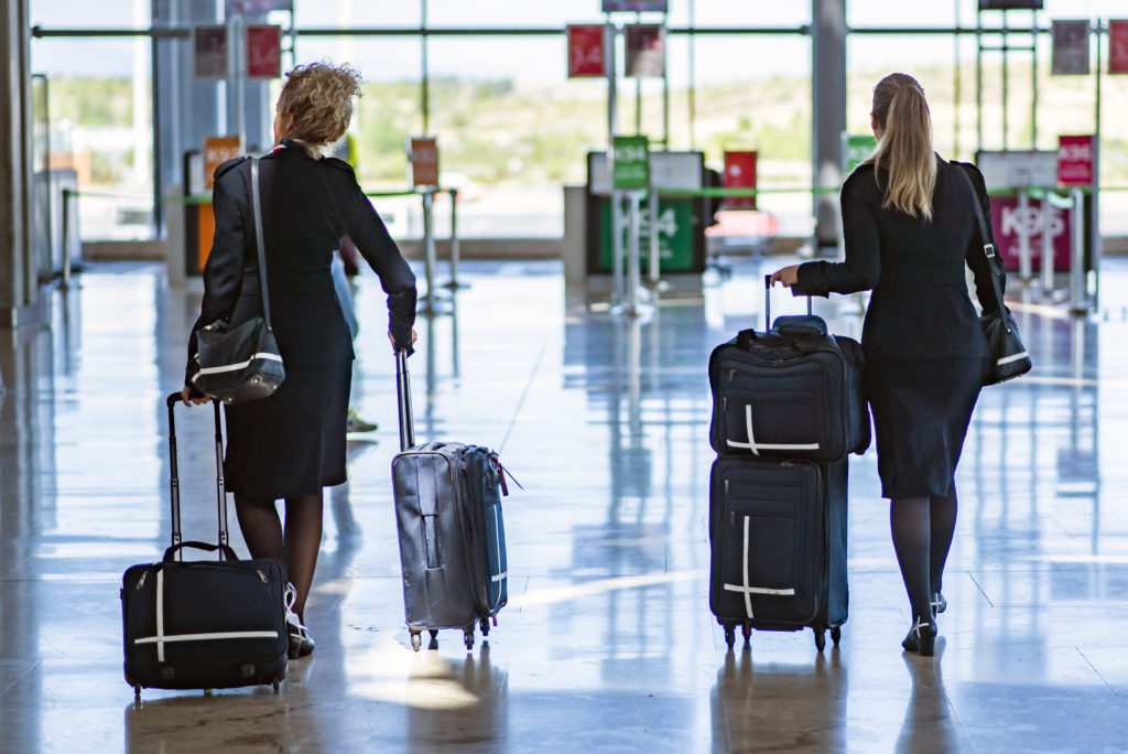 Two flight attendants walking through airport with luggage