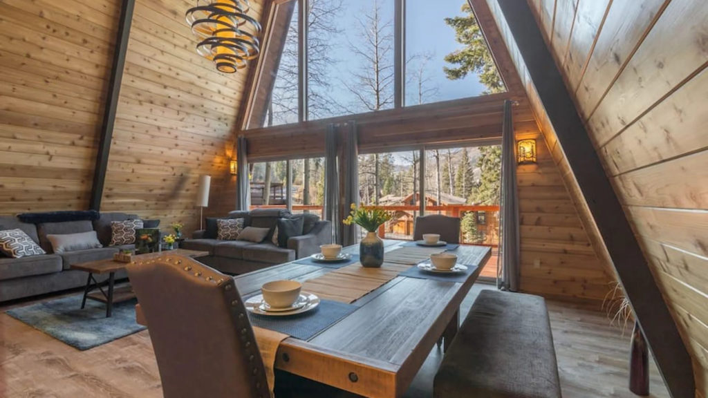Living room of a rustic A-frame cabin with large glass windows