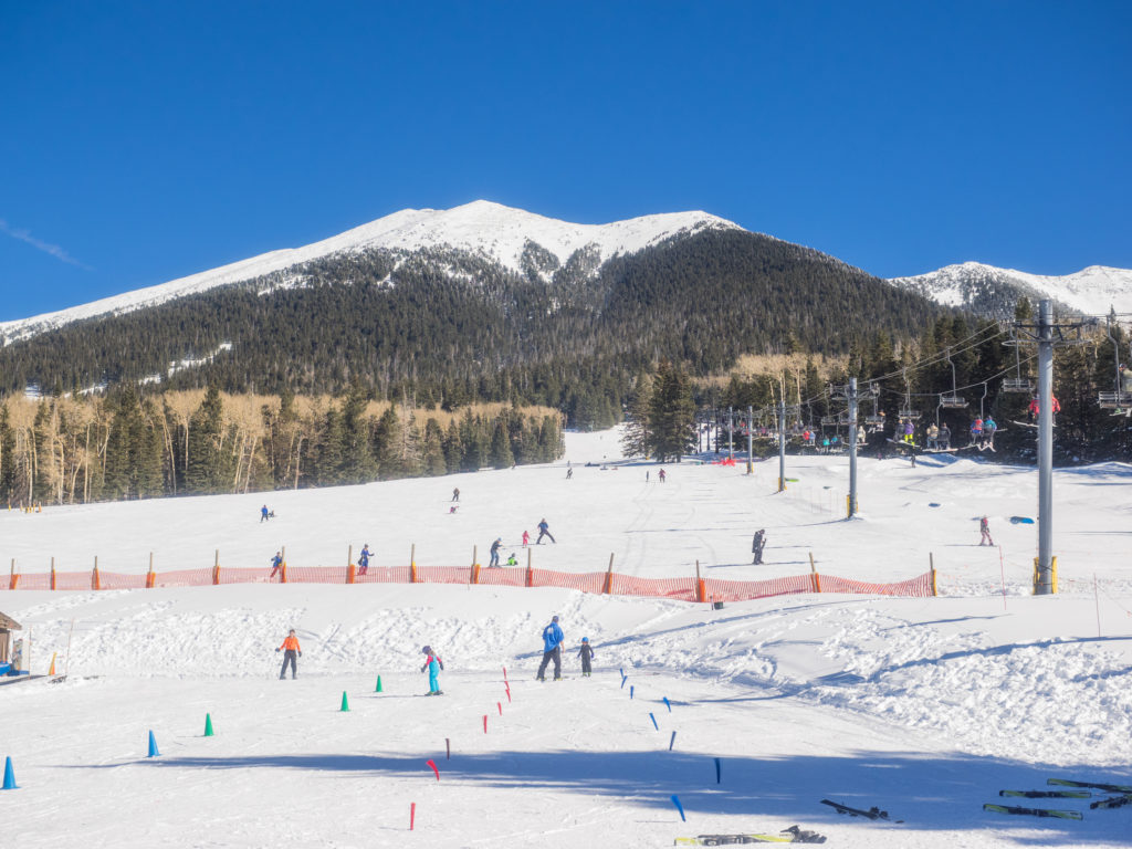Crowd skiing at the Arizona Snowbowl with mountain peak in the background
