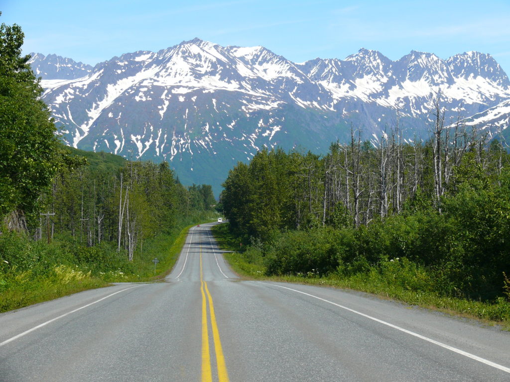 Road leading out of Valdez, Alaska with snowy mountains in the background