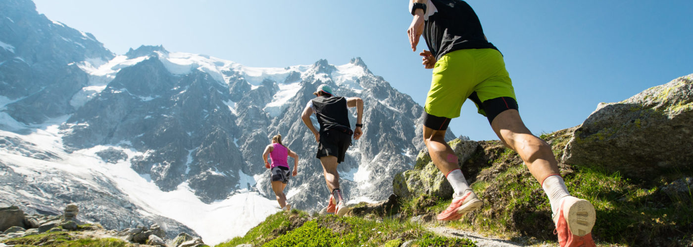 Three trail runners jogging on a mountain trail