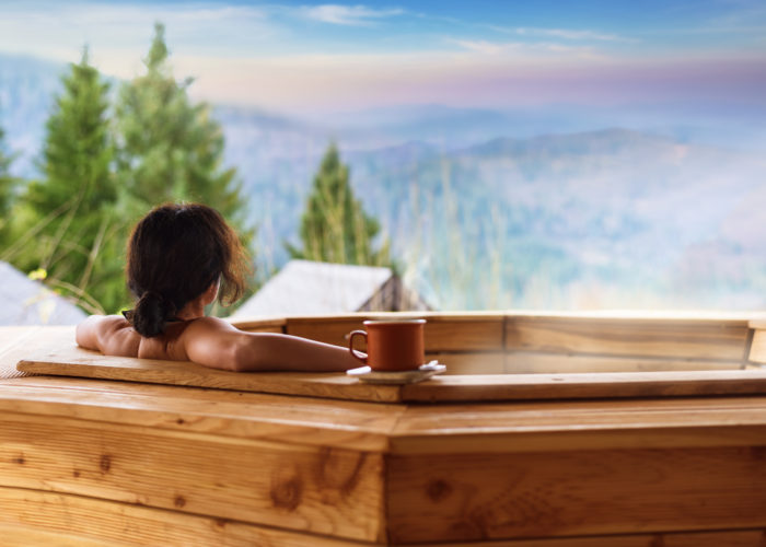 Woman in wooden hot tub with a view of the mountains