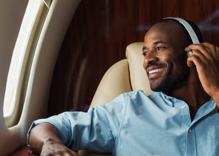Smiling man on plane wearing noise cancelling headphones
