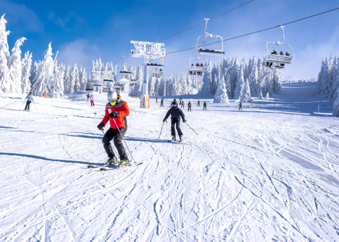 People skiing on a snowy mountain below a ski lift