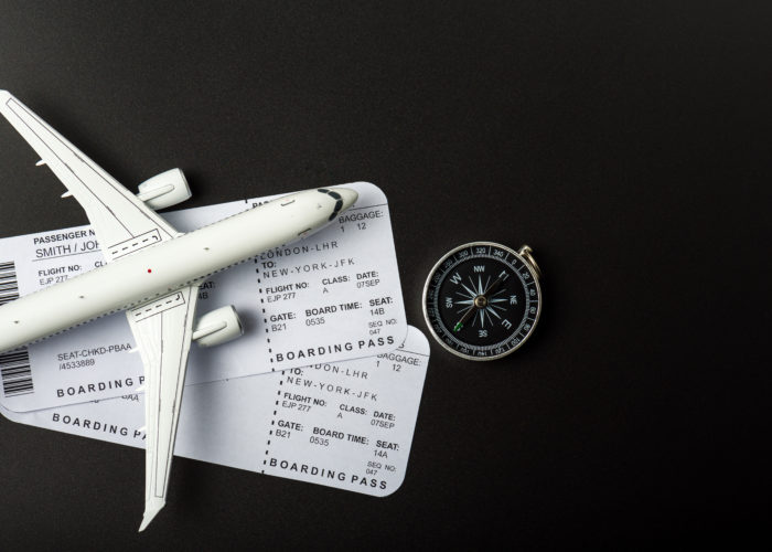 Overhead view of two boarding passes, a model plane, and a compass on a black background