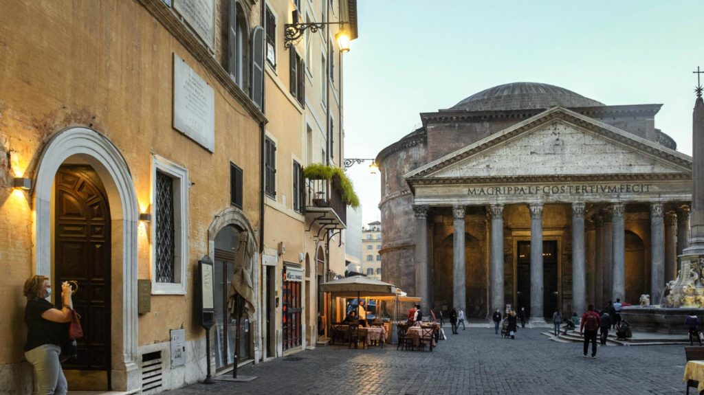 Woman standing outside of The Albergo del Sole and taking pictures of the Pantheon