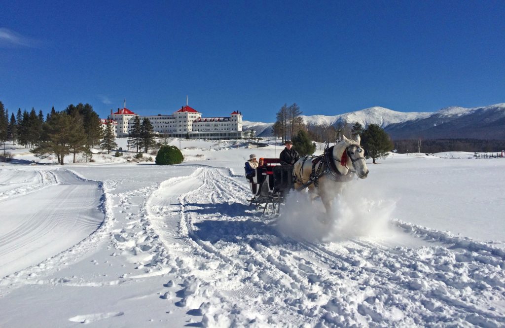 Horse-drawn carriage traveling through the snow in front of the Omni Mount Washington Resort