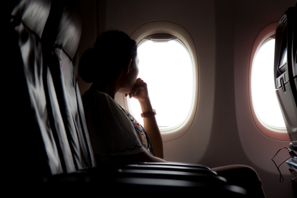 Woman in shadow looking out airplane window