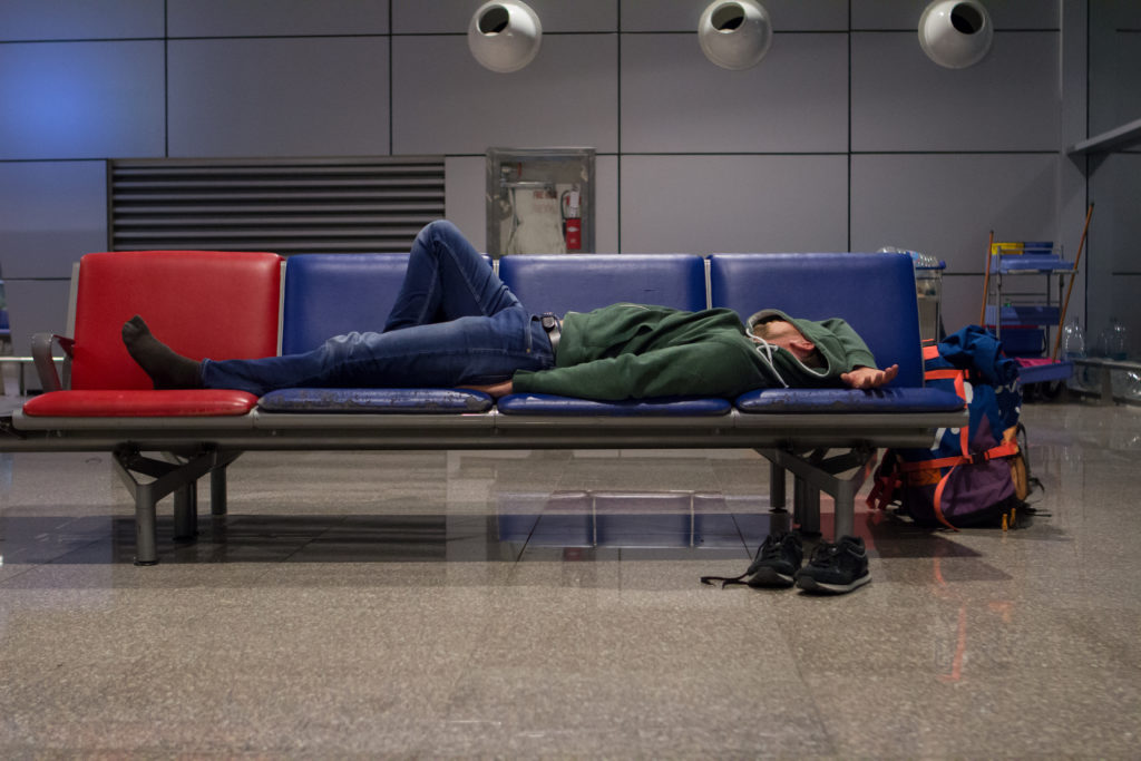 Person sleeping across several seats in an airport terminal