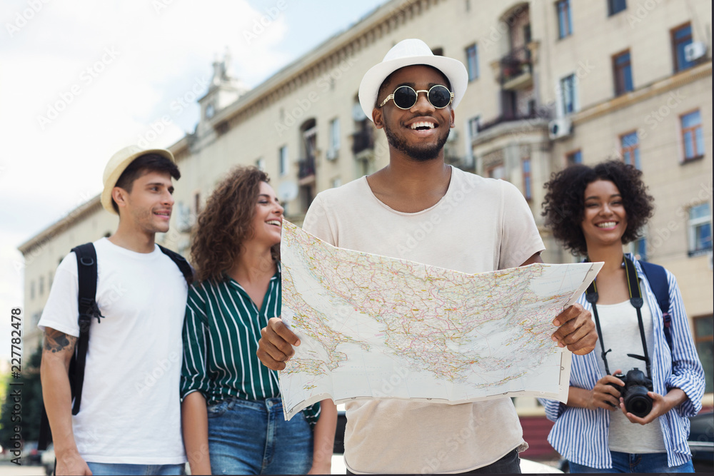 Four friends traveling around a city, smiling and navigating from a map