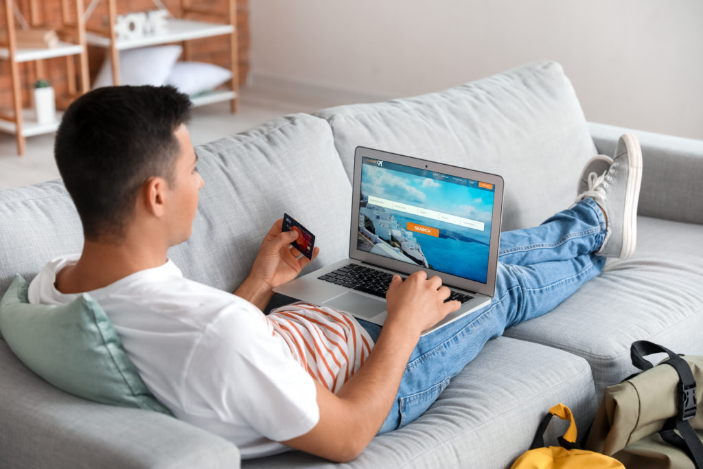 Man resting on couch with his feet up while he books flights online