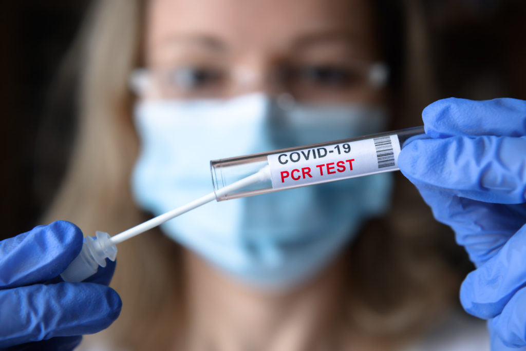 Close up of doctor placing a cotton swab into a test tube for a COVID PCR test