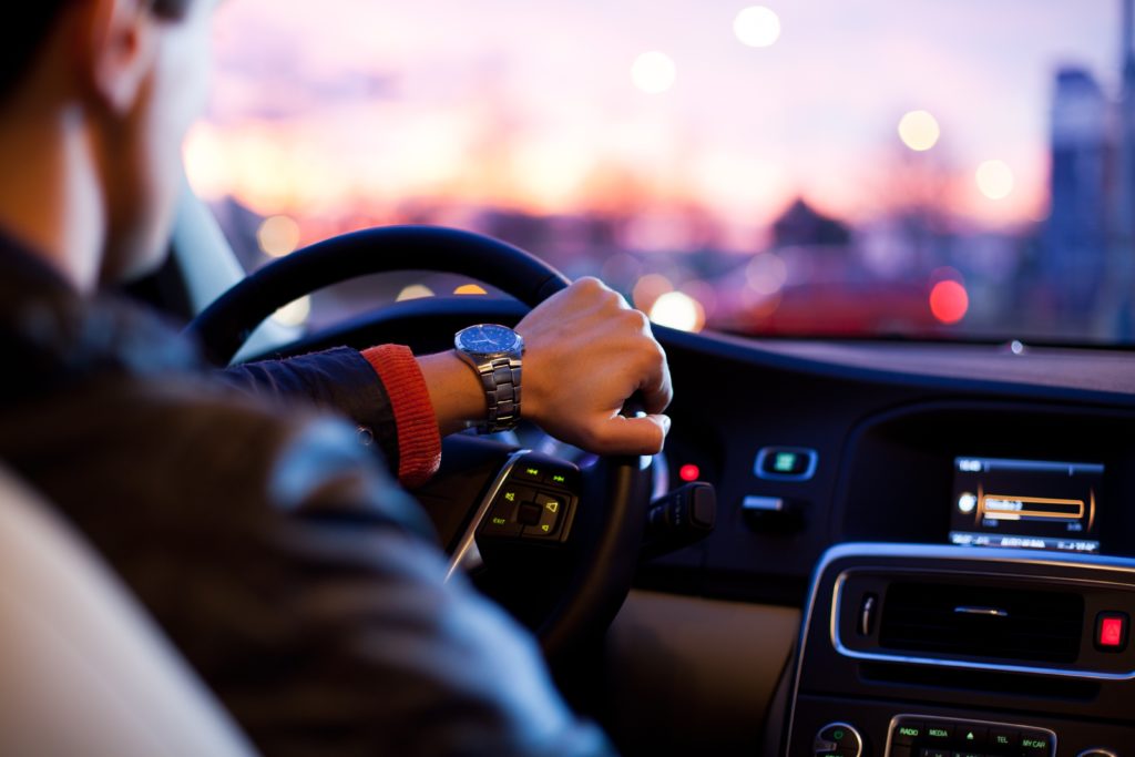 Over the shoulder view of person driving a car at twilight