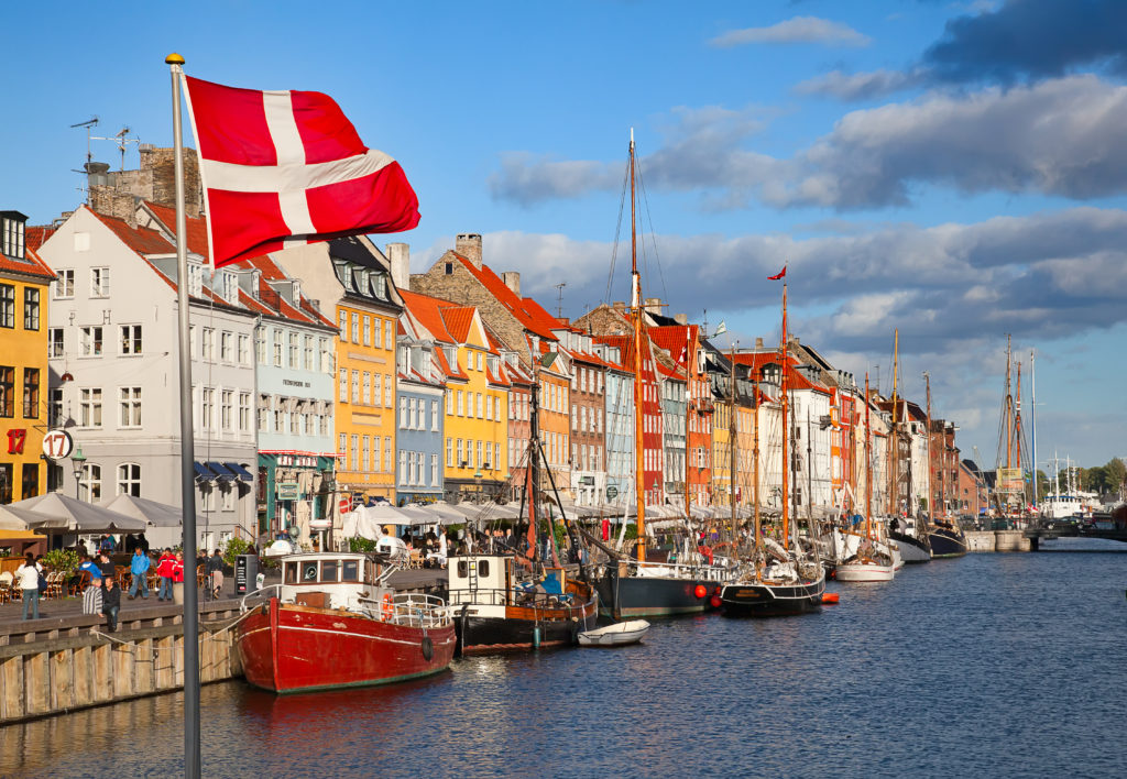 Houses along the water in Copenhagen, Denmark with the Danish flag in the foreground