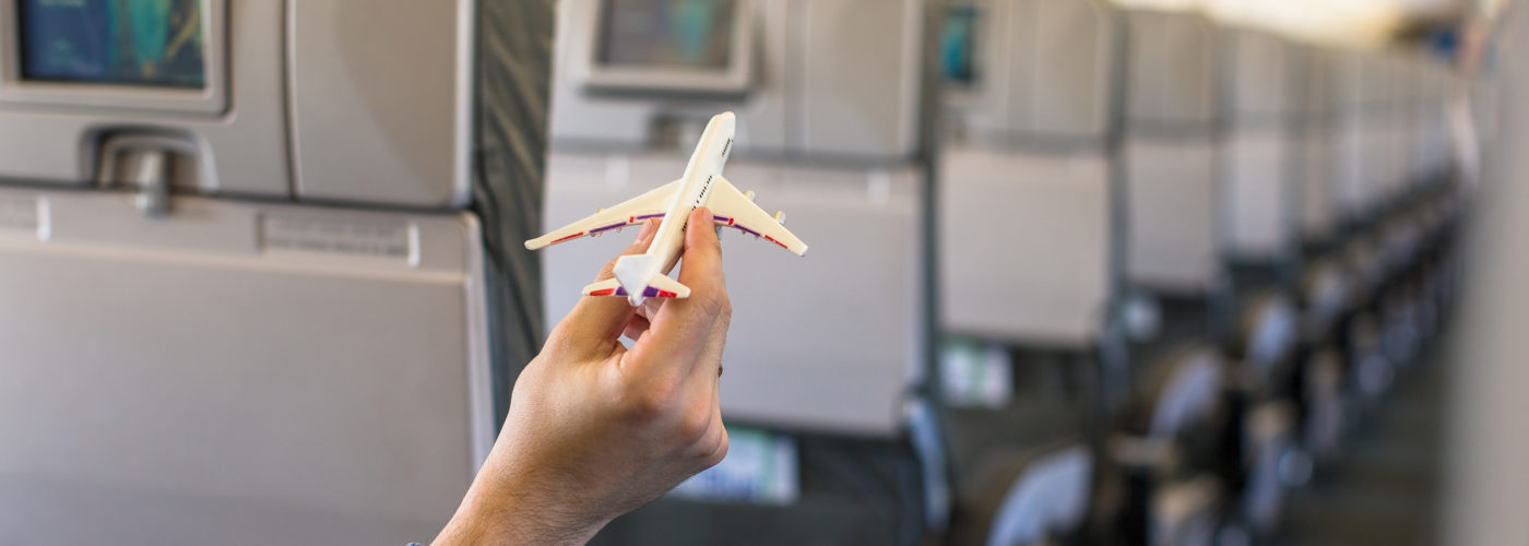 Close up of person's hand holding a model plane inside a real plane