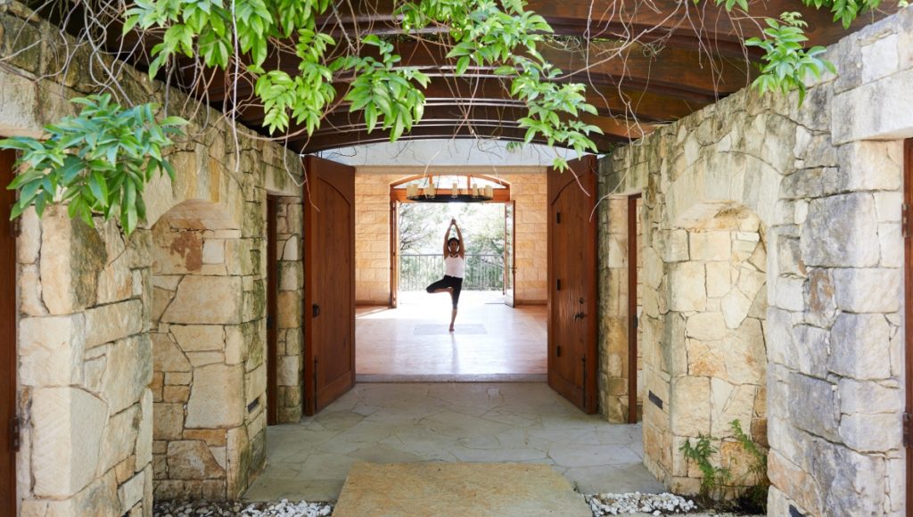 Guest doing yoga under a stone archway at Miraval Austin