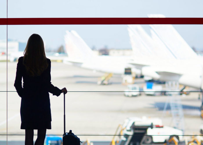 Woman looking out of airport window at planes on runway